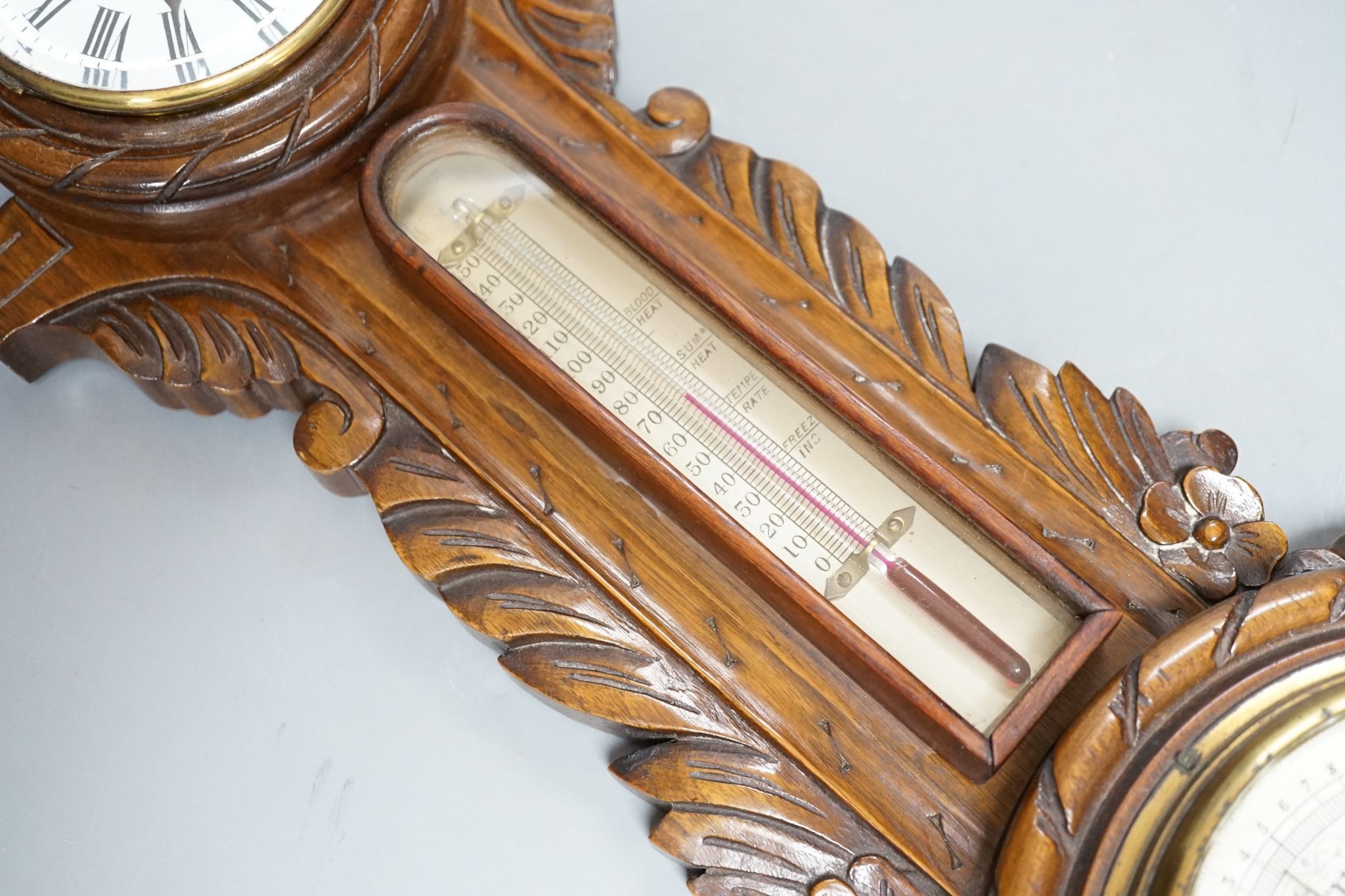 A Victorian carved walnut aneroid barometer with timepiece